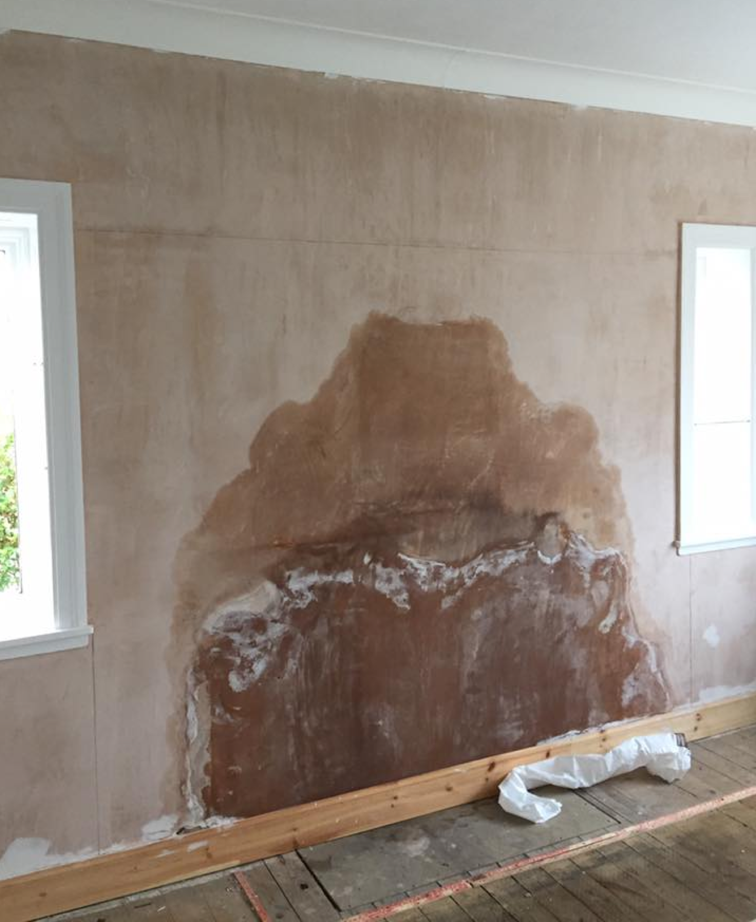 Internal wall with blown plaster and a brown tide mark above the skirting